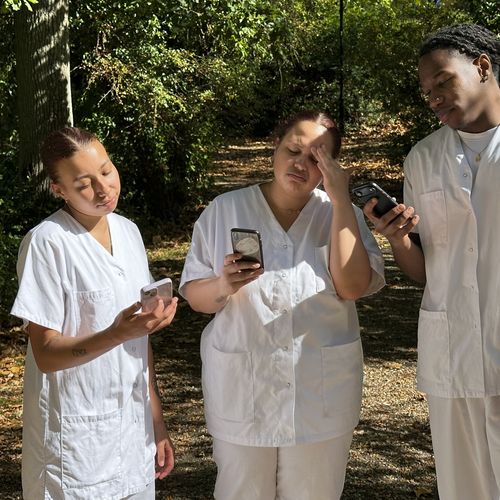 Trois soignants perplexes consultant leurs smartphones à la recherche de solutions